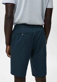 Navy blue shorts made of cotton blend fabric, featuring a back pocket with button closure, elastic waistband, and straight leg design.