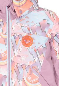 Bunte Skijacke mit geometrischem Muster in Pink, Lila und Blau. Enthält ein orangefarbenes Logo, einen vorderen Reißverschluss und Druckknopfverschlüsse.