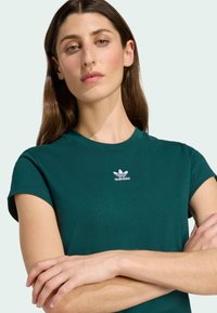 Green cotton t-shirt with a classic fit, short sleeves, and a white Adidas logo on the chest. Soft texture and simple design.