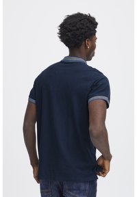 Marine polo skjorte med tekstureret krave, korte ærmer med blå accent og en lige kant. Båret med blå jeans.