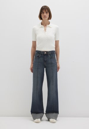 White knitted polo shirt with short sleeves, paired with wide-leg dark denim jeans featuring contrasting seams and frayed hems.