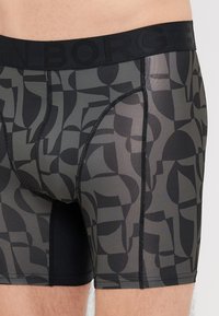 Μαύρες και γκρι boxer briefs με σχέδιο, διαθέτοντας φαρδιά μαύρη ζώνη, με αφηρημένο σχέδιο και αντίθετο πλέγμα στο κάτω μέρος.