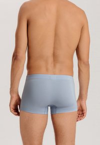 Ljusblå bomullsboxer med åtsittande design och elastisk midjeband, synlig sömnad och slät yta. Bakvy utan ytterligare detaljer.
