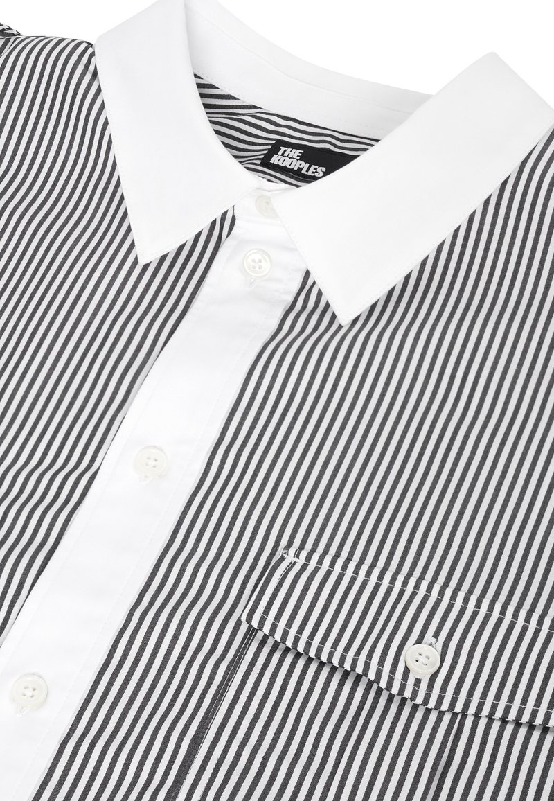 Camicia a righe verticali bianco e nero con colletto bianco, pattina con bottoni e taschino sul petto con bottoni.