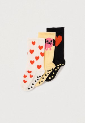 Three pairs of socks with anti-slip dots: white with red hearts, yellow with a pink dog, and black with a large red heart.
