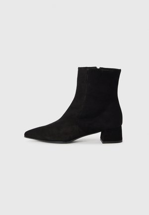 Botte de cheville en daim noir avec un bout pointu, un petit talon carré et une fermeture éclair sur le côté. Texture lisse sans motifs ni accents visibles.
