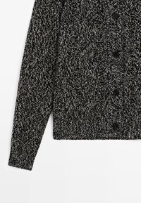 Cardigan nero e bianco a maglia lavorata a trecce, con maniche lunghe, chiusura con bottoni frontali, orlo a coste e motivo strutturato.