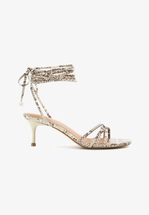 Sandalo con tacco alto, punta aperta, motivo pelle di serpente, con sottili cinturini e laccetti che avvolgono la caviglia, in tonalità neutre beige e grigie.