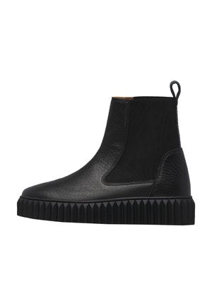 Stivaletto alla caviglia in pelle nera con suola zigrinata, pannello laterale elastico e linguetta sul retro, mostrato dal lato esterno.
