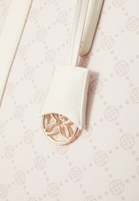 Sac blanc avec un motif texturé de petits cercles et points. Doté d'une bandoulière en cuir crème et d'un accent en métal doré.