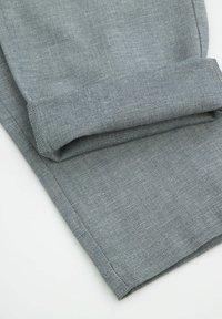 Szara tkanina dżinsowa z subtelnym wzorem w jodełkę, z podwiniętymi mankietami i czystymi, równymi szwami wzdłuż krawędzi.