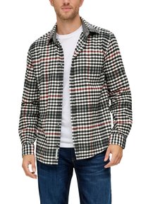 Zwart-wit geblokte flanellen shirt met rode accenten, lange mouwen en knopen aan de voorkant. Gecarryeerd over een witte t-shirt, gecombineerd met blauwe jeans.