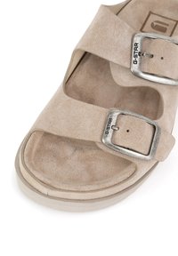 Beez suede sandaalid, millel on kaks laia rihma hõbedase metallist lukuga ja tekstureeritud tallaga. Ümar varvas ja kerge põhi mugavuse jaoks.