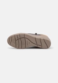Suela de zapato de goma marrón con una superficie texturizada, que presenta agujeros de drenaje, ranuras para tracción y la marca Geox.