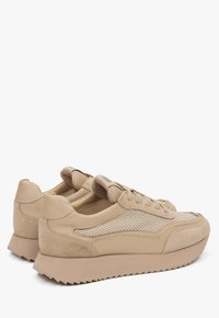 Beige sneakers met leren en mesh materialen, ronde neus, textuur op de body en een minimalistisch design met een dikke, geribbelde zool.