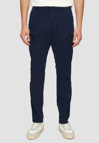 Granatowe spodnie cargo wykonane z mieszanki bawełny, z bocznymi kieszeniami, prostym krojem nogawek i standardowym paskiem, połączone z białymi trampkami.