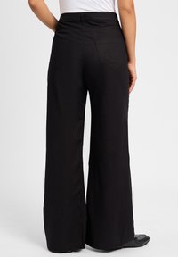 Zwarte wijde broek met een gladde textuur, voorzien van een hoge taille, twee achterzakken en een eenvoudig ontwerp zonder versieringen.