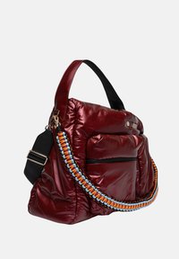 Rode luxe schoudertas met een glanzende afwerking, voorzien van een dikke, veelkleurige gevlochten band, zwarte accenten en een voorzak met ritssluiting.