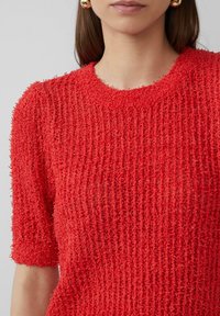 Rood gestructureerd T-shirt met korte mouwen en een geribbelde structuur. Ronde halslijn en losse pasvorm, gemaakt van een zachte, lichte stof.