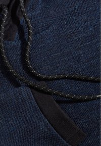 Marineblaues Sweatshirtmaterial mit strukturiertem Strickmuster, ausgestattet mit einer schwarzen Kordel mit geflochtenem Design und schwarzen Akzenten an den Kanten.