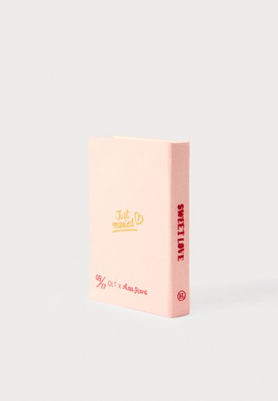 Livre à couverture rigide rose avec du texte doré et rouge sur la couverture. L'avant indique "Just married" avec un cœur ; le dos dit "SWEET LOVE." Surface texturée.