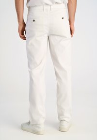 Witte katoen broek met een rechte snit, twee achterzakken met knoopsluitingen en een gladde textuur. gedragen met witte sneakers.