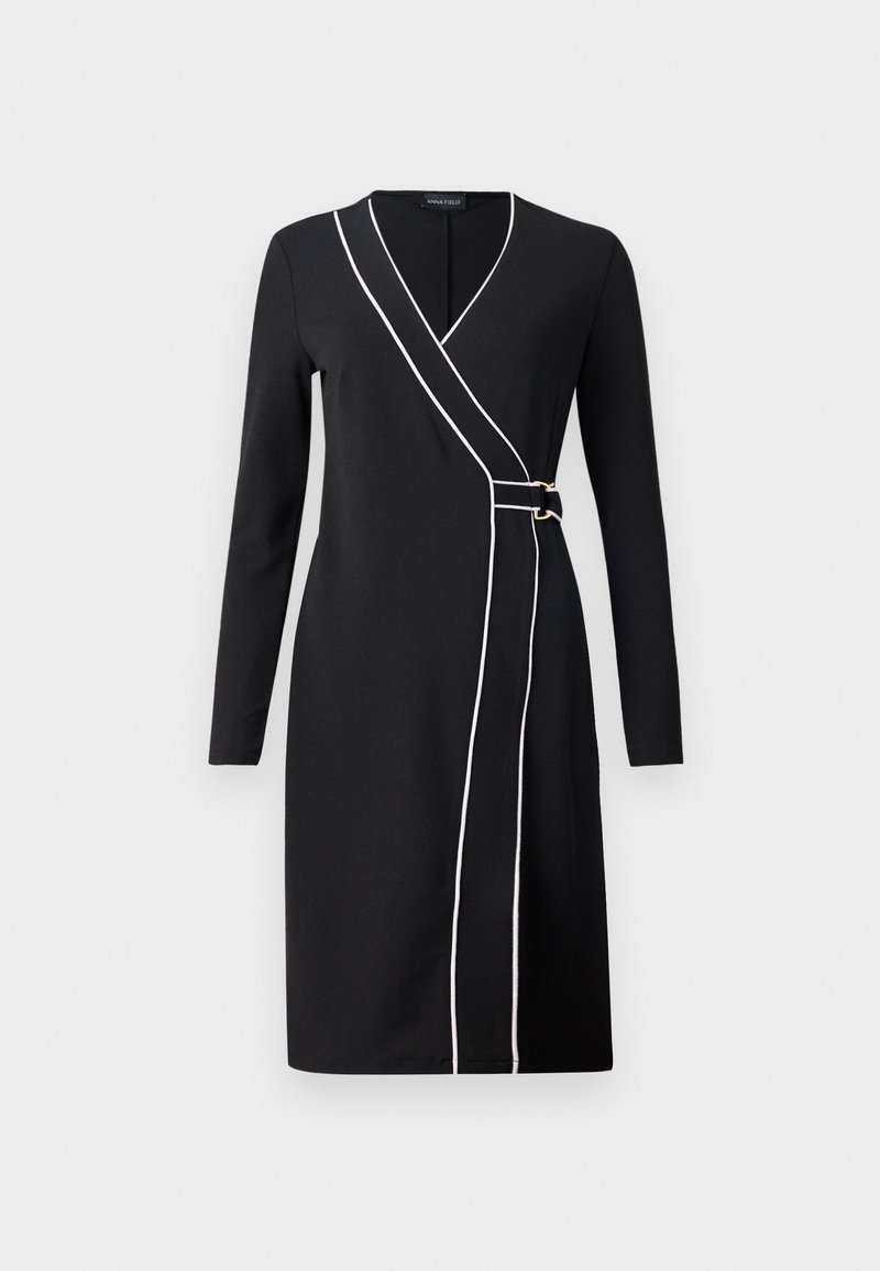 Vestido negro ajustado con mangas largas, con ribetes blancos en el frente y detalles en tono dorado. Tejido suave y tejido, diseño hasta la rodilla.