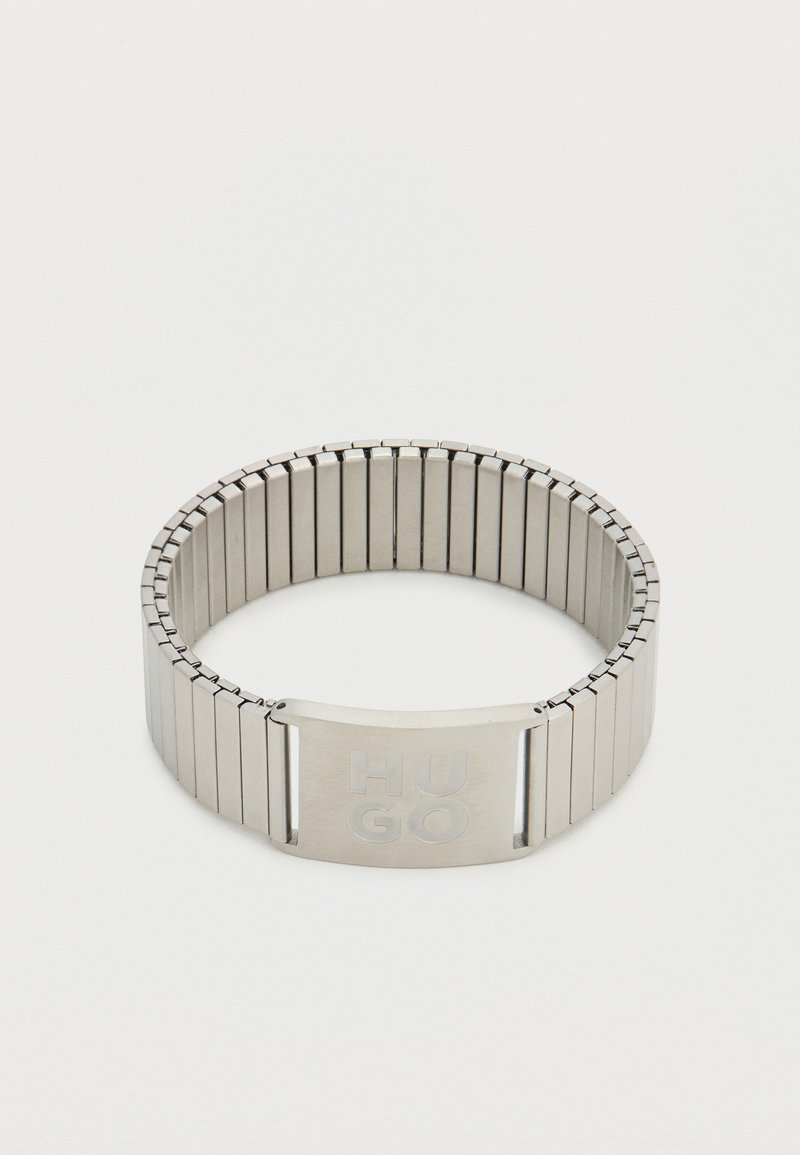 Μεταλλικό βραχιόλι με ευέλικτη μπάντα, με ματ ασημί φινίρισμα. Χαραγμένο "HUGO" σε ορθογώνιο κούμπωμα. Κομψός και μοντέρνος σχεδιασμός.