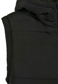Veste sans manches noire matelassée avec un col montant et des surpiqûres horizontales visibles sur le tissu.