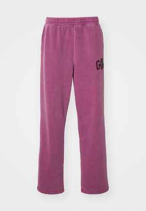 Pantaloni della tuta viola con vestibilità rilassata, dotati di una cintura elastica e tasche laterali. Un accento del logo scuro è presente sulla gamba sinistra.