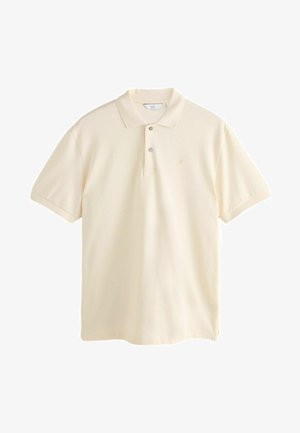 Polo shirt in cream color made of soft fabric. Features a two-button placket, short sleeves, and a subtle embroidered logo on the chest.