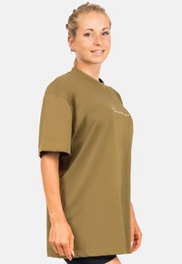 T-shirt oversize verde oliva realizzato in tessuto liscio, con maniche corte e collo a giro. Logo discreto sul davanti.