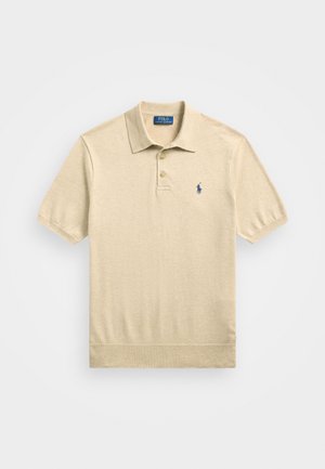 Beżowa koszulka polo wykonana z miękkiego materiału, z zapięciem na dwa guziki, krótkimi rękawami i granatowym logo po lewej stronie klatki piersiowej.