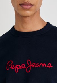 Camiseta de algodón navy con el texto bordado en rojo "Pepe Jeans" en el pecho, con cuello redondo y textura suave.