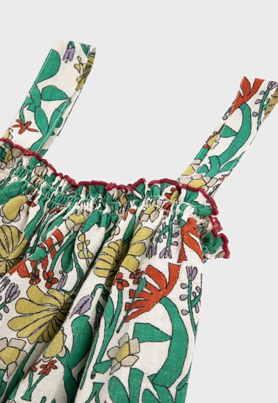 Gros plan d'une robe sans manches à motif floral avec des fleurs vertes, jaunes, orange et violettes, et une bordure volantée rouge sur les bretelles et le décolleté.