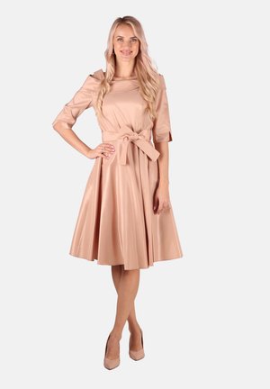 Ein beiges, satiniertes, knielanges Kleid mit kurzen Ärmeln und einem gebundenen Taillengürtel. Der ausgestellte Rock hat sanfte Falten für Volumen und Bewegung.