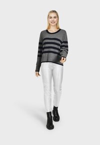 Grijze en marineblauwe gestreepte trui met een ronde hals, gecombineerd met glanzende zilveren broek en zwarte enkellaarsjes. Eenvoudig en modern ontwerp.