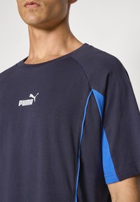 Marineblauw T-shirt met korte mouwen en een blauwe zijpaneel, met een wit Puma-logo op de borst. Gemaakt van zachte, ademende stof.