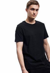 Svart bomullst-shirt med korta ärmar, rund halsringning och en slät yta. Enkelt design, något figursydd form, inga synliga mönster.