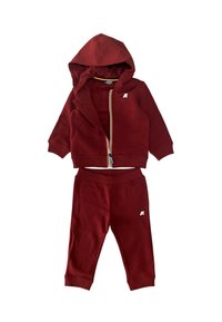 Tuta in cotone rosso con giacca con cappuccio e zip abbinata e pantaloni coordinati. La giacca presenta un logo bianco; i pantaloni hanno polsini e vita a costine.