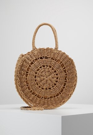 Rond geweven strohandtasje met bovenhandvat en schouderriem, met een cirkelvormig gevlochten patroon in natuurlijke tan kleur.