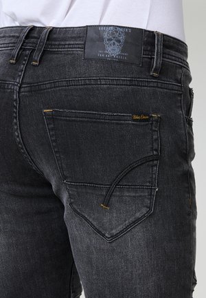 Must mustripped denim teksastiga, millel on sobitatud disain, kontrastne õmblus ja eristuv tagatasku koos aktsendi detailiga.