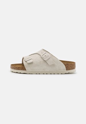 Suede gray slide sandal with two adjustable buckle straps, a textured cork footbed, and a white rubber outsole featuring a wavy pattern.