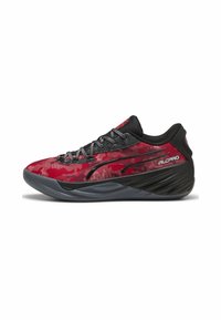 Baskets de sport rouge et noir avec un motif camouflage, un dessus en tissu texturé, un design épuré et une semelle en caoutchouc pour l'adhérence.