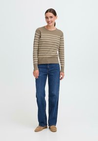 Gestreifter Strickpullover in Olivgrün und Creme, runder Halsausschnitt; kombiniert mit blauen geraden Jeans und hellbraunen Loafern.