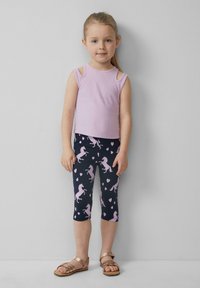 Lavendelkleurige mouwloze top met uitsnijdingen op de schouders, gecombineerd met marineblauwe leggings met roze eenhoorns en harten; kind draagt bruine sandalen.
