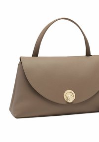 Bolso de mano de piel beige con solapa plegable, cierre redondo dorado y un asa superior única; textura suave y forma estructurada.