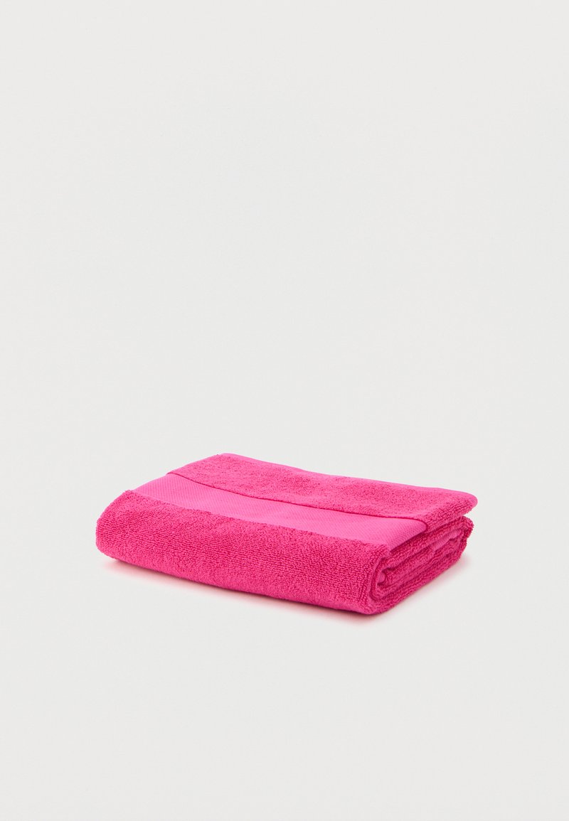 Bright pink folded towel with a smooth band across the middle, placed on a plain white background.