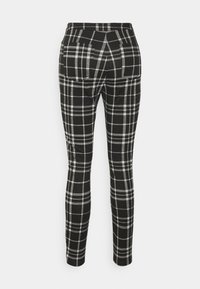 Svart och vit rutiga byxor med slim fit, som har två bakfickor och en medelhög midja, tillverkade av mjukt tyg.