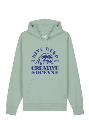 Light green hoodie with front pocket and navy text saying "Dive deep into your creative ocean" with a wave graphic above the text.